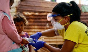 Albanis Oliva, a coordinator at a local NGO which provides health assistance to communities in northwest Venezuela, helps young children clean their hands during the COVID-19 pandemic.
