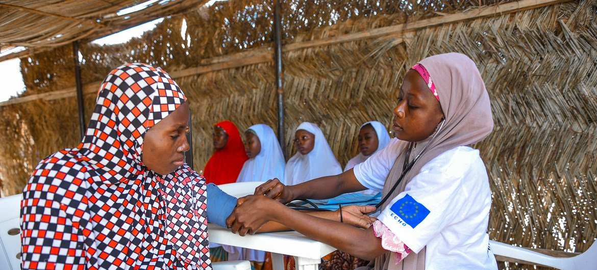 Trabajadora de salud asistiendo a una mujer embarazada en una clínica de Nigeria.