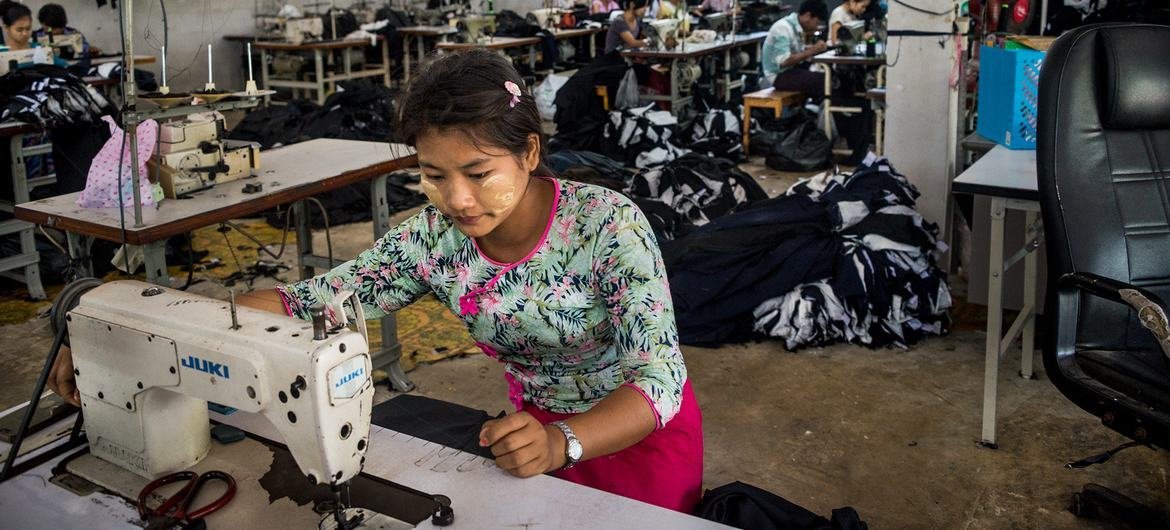 عاملة مهاجرة تخيط الملابس في مصنع غربي تايلاند. بالرغم من ساعات العمل الطويلة إلا أن هؤلاء العمال يكسبون أقل من الحد الأدنى للأجر اليومي، مما يترك لهم بالكاد ما يكفي من المال للإيجار أو الطعام أو المدخرات.