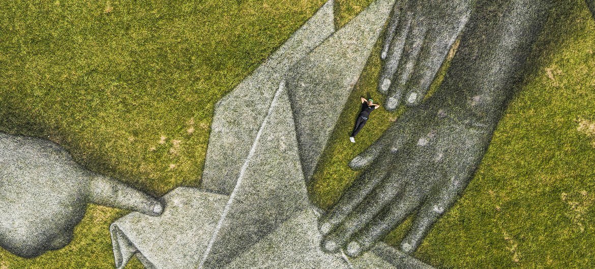 L'artiste franco-suisse Saype (Guillaume Legros) pose dans sa fresque géante éphémère intitulée "World in Progress II" sur la pelouse du Siège de l'ONU à New York.