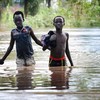 在埃塞俄比亚马班县的难民营中，两个男孩在没过膝盖的洪水中行走。