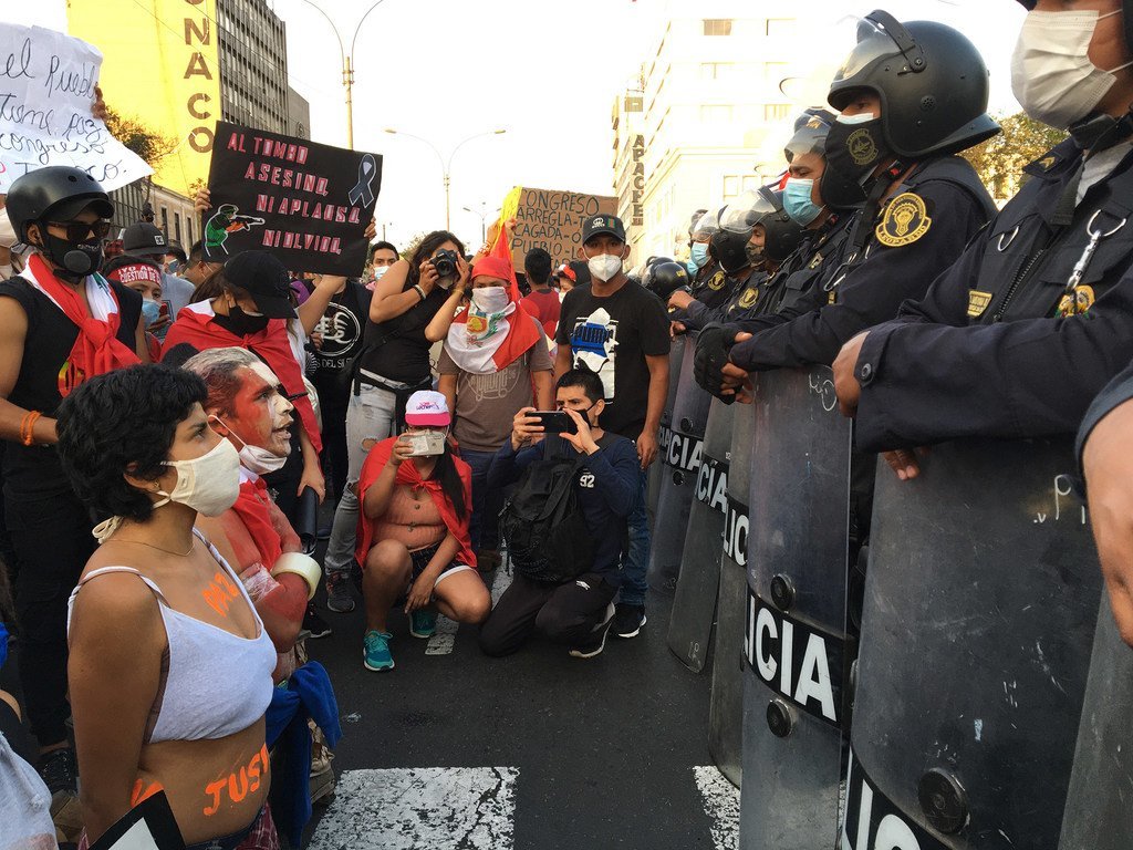 Un groupe de manifestants agenouillés devant la police.