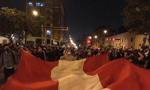 Manifestantes despliegan una bandera de Perú.