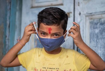 An 11-year-old boy in India demonstrates the correct way to wear a mask. 