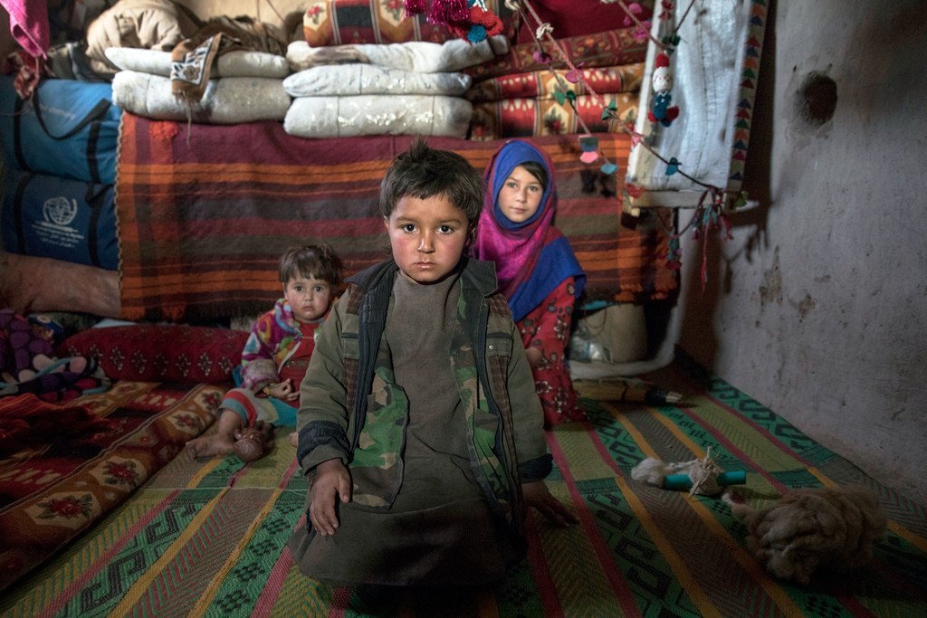Tres hermanos sentados en el que es se ha convertido en su hogar, en un campamento de desplazados internos en las afueras de la ciudad occidental de Herat, en Afganistán.