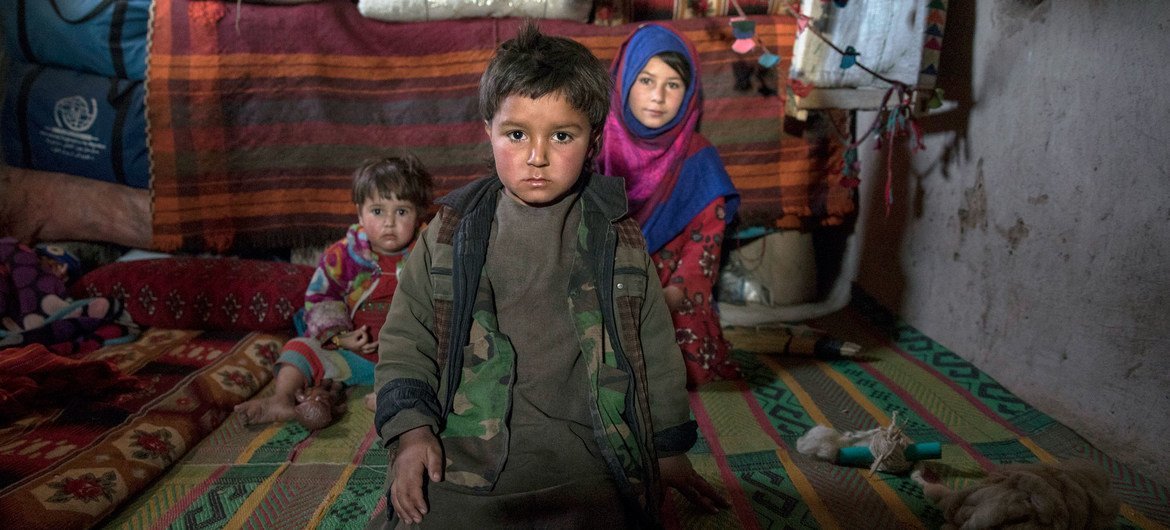 Tres hermanos sentados en el que es u hogar en un campamento de desplazados internos en las afueras de la ciudad occidental de Herat, en Afganistán.