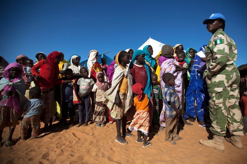 Une Casque bleue du Nigéria avec des femmes et des enfants à la base de la MINUAD, à Labado, dans la région du Darfour, au Soudan.
