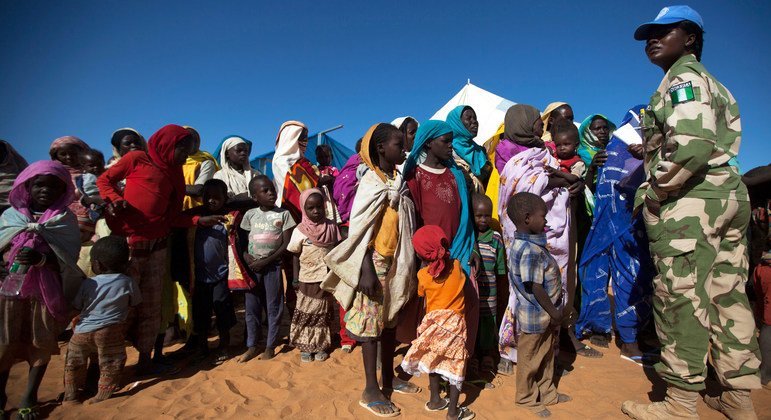 Une Casque bleue du Nigéria avec des femmes et des enfants à la base de la MINUAD, à Labado, dans la région du Darfour, au Soudan.