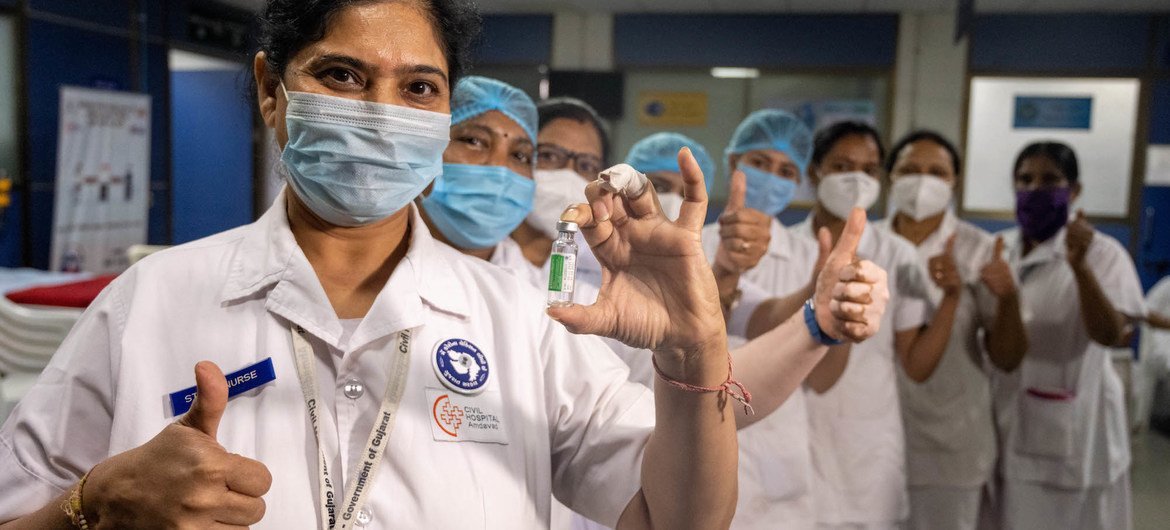 Health workers pose with a vial of COVID-19 vaccine after receiving their shots at a hospital in India.