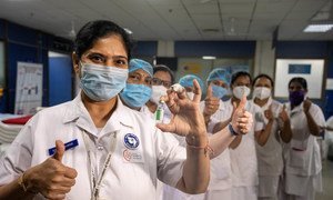 Health workers pose with a vial of COVID-19 vaccine after receiving their shots at a hospital in India.