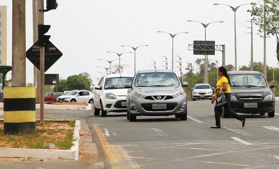 A woman rushes across a busy road in Brazil.