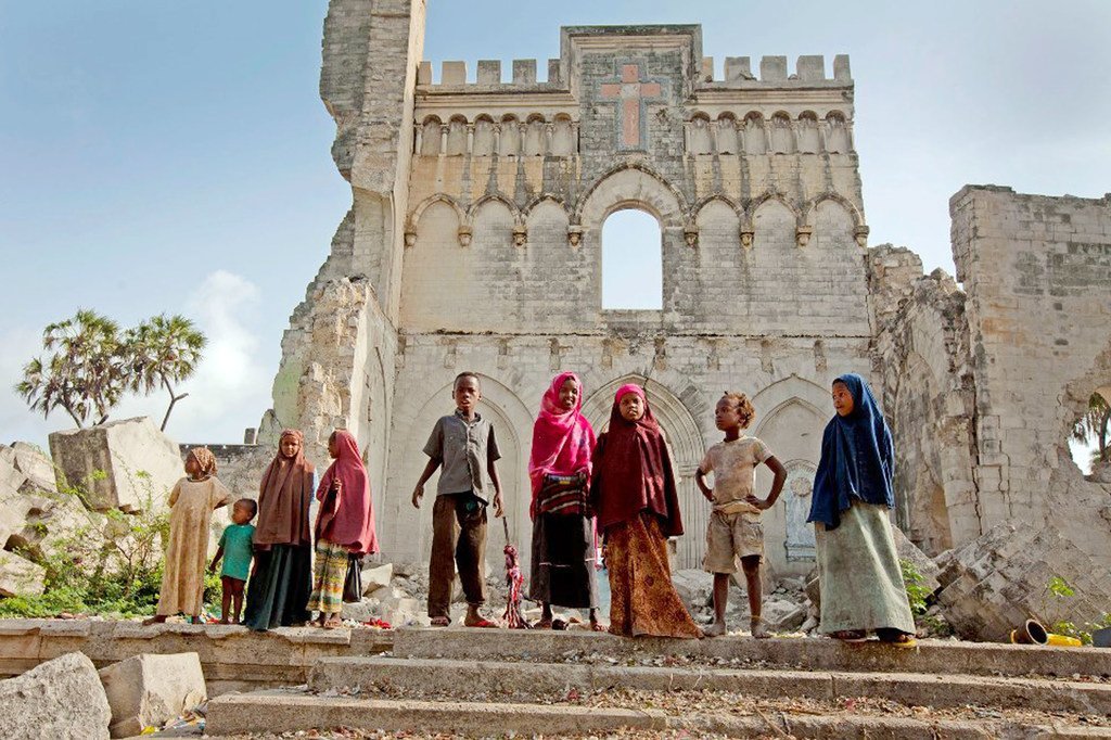 索马里的儿童站在意大利殖民时期修建的摩加迪沙大教堂遗迹前。