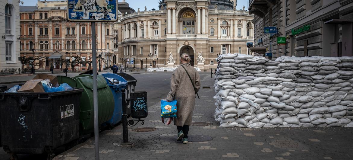 Mulher passa por sacos de areia empilhados para proteção, em Odessa, Ucrânia