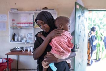 肯尼亚瓦吉尔的一位母亲带着她的孩子去健康中心称体重。