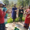 सहकर्मी शिक्षक मालती अपने समुदाय में कोविड सम्बन्धी जागरूकता फैलाने के लिये, लोगों को हाथ धोने की सही तकनीक सिखा रही हैं.