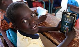 Des enfants vont en classe avec leurs tablettes à l’école Radi, dans le village de Safi, dans le sud du Niger.
