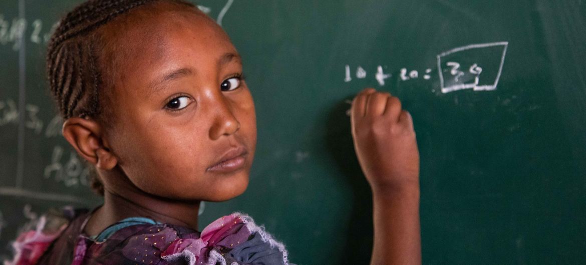 इथियोपिया के टीगरे के एक स्कूल में छोटी बच्ची, यूनीसेफ़ समर्थित स्कूल में बोर्ड पर कुछ लिख रही है.