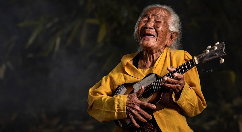 इण्डोनेशिया में एक वृद्ध महिला वाद्य यन्त्र बजाते हुए