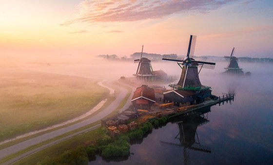 Morning mist rises across fields in rural Netherlands.