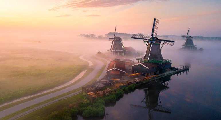 Morning mist rises across fields in rural Netherlands.