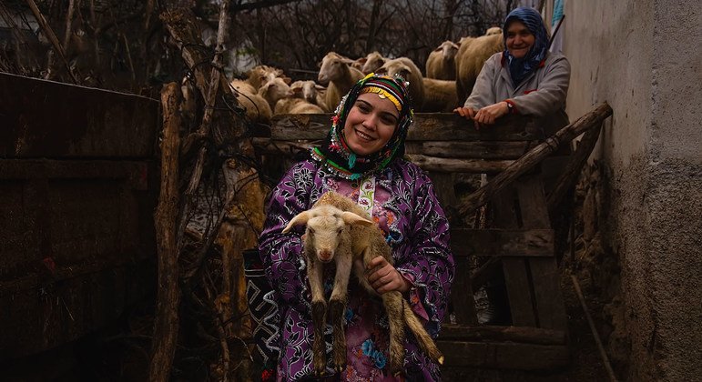 A woman in traditional dress in rural Turkey holds one of her animals.