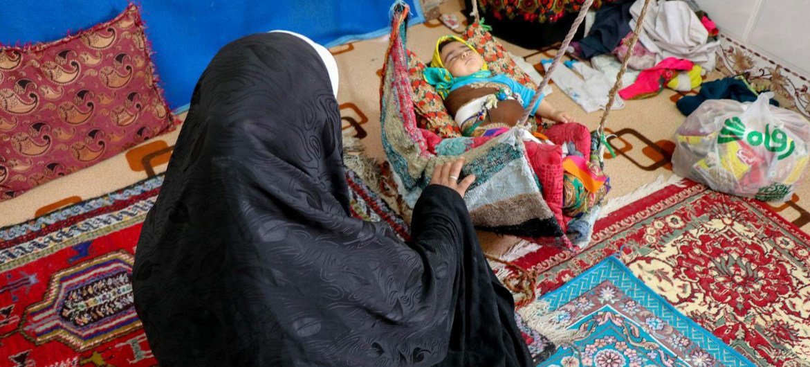 A mother of six tends to her youngest child in Khorasan Province in Iran.