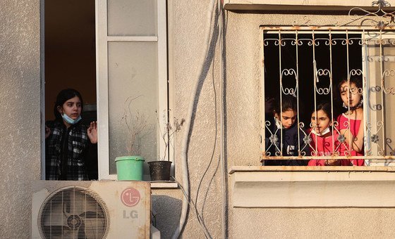 کودکان فلسطینی از پنجره خانه خود به ساختمان های ویران شده در محله خود در شهر غزه نگاه می کنند.