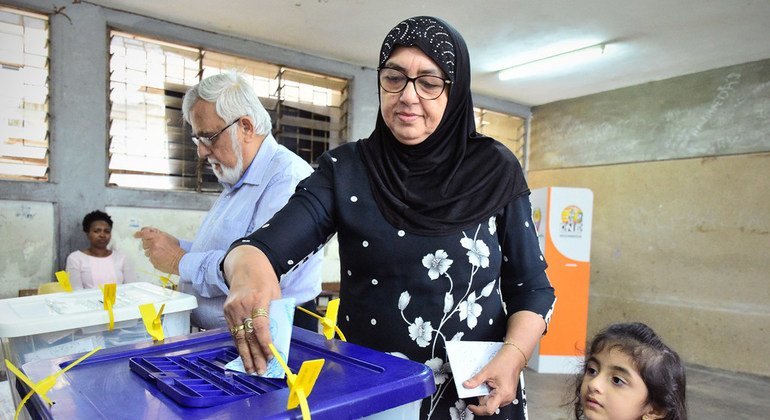 Mulher acompanhada de uma criança participa da votação durante as eleições gerais em Moçambique. 