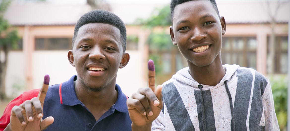 Jovens moçambicanos mostram o dedo marcado com a tinta azul após votarem nas eleições gerais em Moçambique.  
