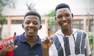 Jovens moçambicanos mostram o dedo marcado com a tinta azul após votarem nas eleições gerais em Moçambique.  