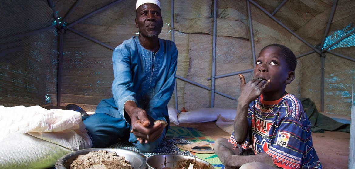 Zore Yusef partage un repas avec un de ses enfants. Le conflit armé a forcé sa famille à fuir la région nord du Burkina Faso.