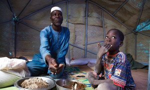 Zore Yusef compartilha uma refeição com um de seus filhos. O conflito armado forçou sua família a fugir da região norte de Burkina Faso.