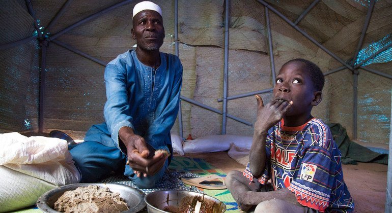 Zore Yusef shares a meal with one of his children. Armed conflict forced his family to flee the northern region of Burkina Faso. 