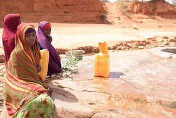 Young girls wait by a shallow well during a humanitarian mission in drought-affected Garbahaarey, a town in southern Somalia.