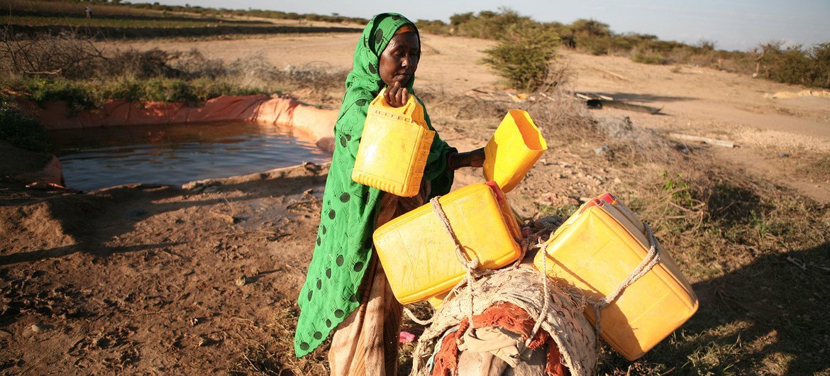 Somalian woman filling water in cans.