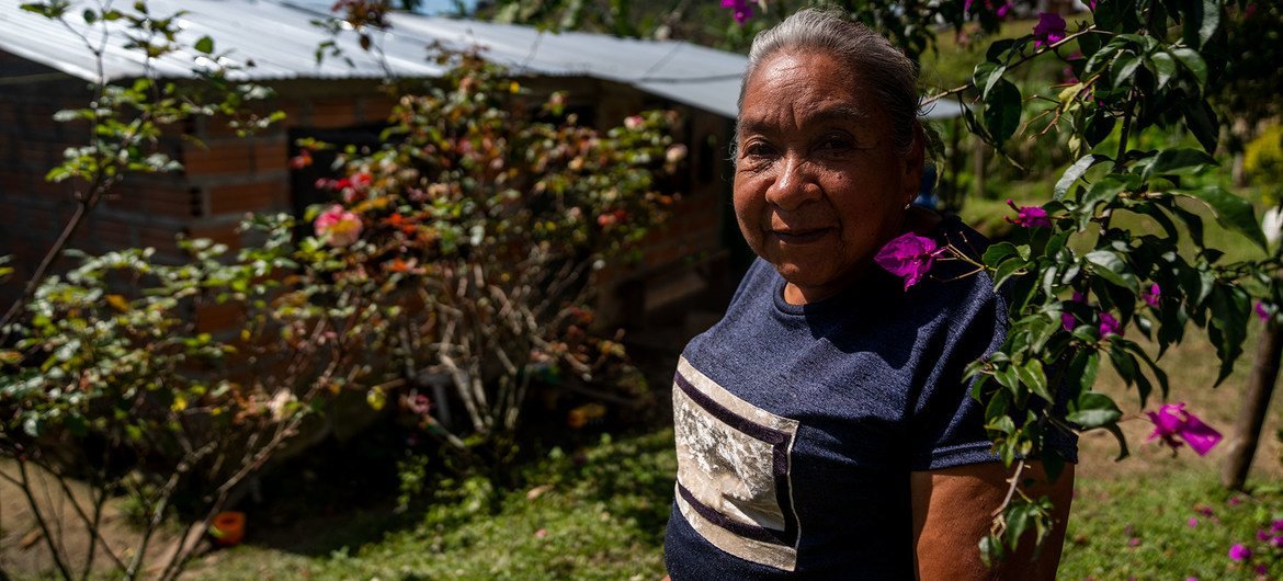 Farmer and conflict victim Lucila stands outside her house which was rebuilt after the peace process in Colombia.