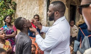 A child is administered an oral vaccine against cholera as part of a large-scale vaccination campaign.