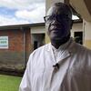 Portrait de Dr. Denis Mukwege, médecin congolais, devant UN bâtiment en briques.