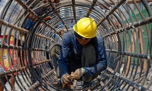 A construction worker builds a cylindrical metal structure in Yangon, Myanmar.