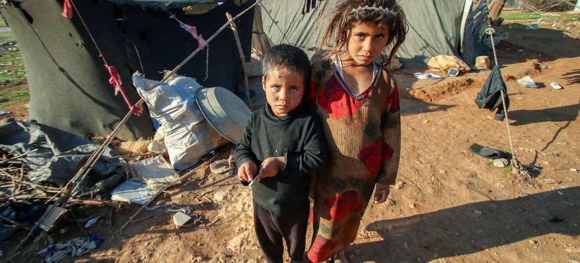 Children stand outside the tent where they live in a remote desert camp in southern rural Homs, Syria.