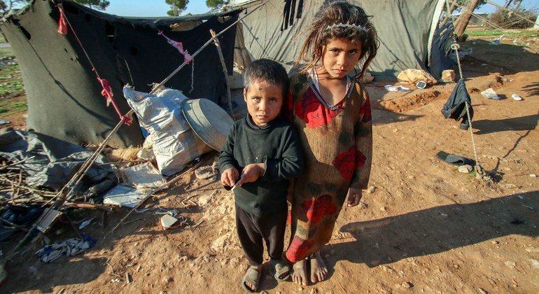 أطفال يقفون خارج الخيمة التي يعيشون بها في مخيم صحراوي بعيد في ريف حمص الجنوبي، بسوريا.