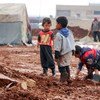 أطفال يلعبون في الوحل في مخيم للنازحين يقع شمال حلب، سوريا.