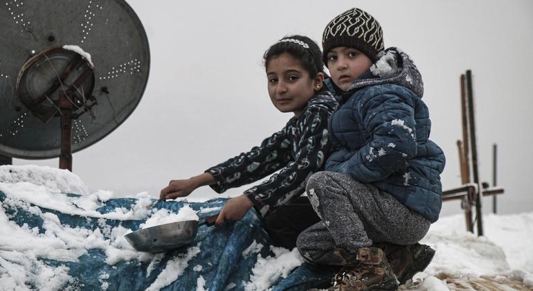 طفلان في مخيم كللي في إدلب في شمال غرب سوريا يحاولان إزالة الثلوج عن الخيمة.