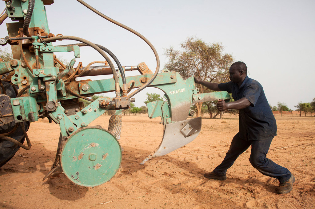 Unos trabajadores preparan los tractores para empezar a arar en Burkina Faso.