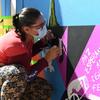 Una mujer pinta un mural por la Paz y la Reconciliación en Colombia.