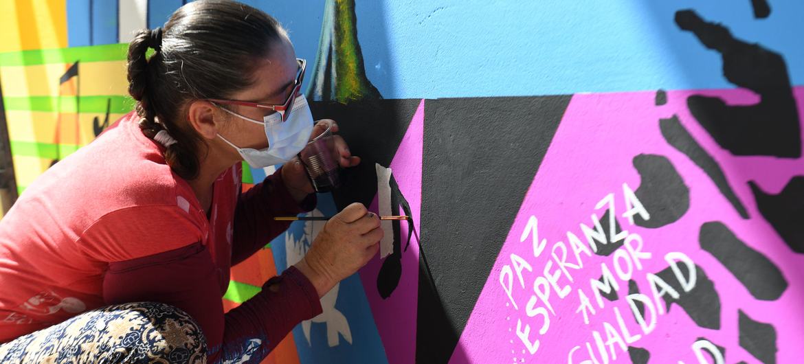 Una mujer pinta un mural por la Paz y la Reconciliación en Colombia.