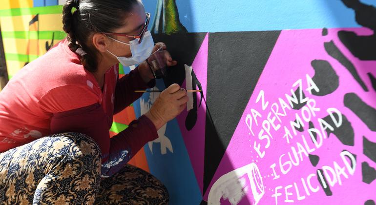 A woman paints a mural for Peace and Reconciliation in Colombia.