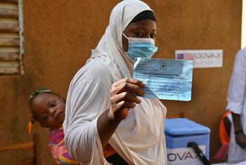امرأة ترفع شهادة تطعيم ضد مرض كوفيد -19 في مركز صحي في منطقة أوباسين في بوركينا فاسو.
