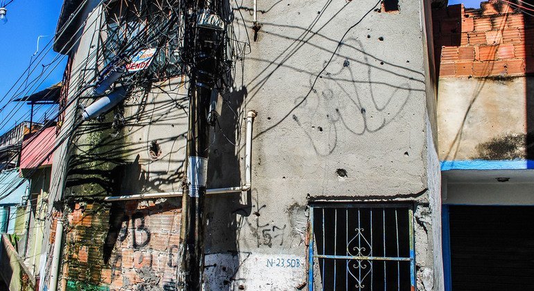 La fachada de un edificio tiroteado repetidas veces con un grafiti con la palabra paz.