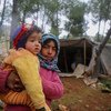 2020年2月7日，一名女童抱着一个比自己年龄更小的孩子。叙利亚伊德利卜南部及阿勒颇西部的战事使得大批家庭被迫流离失所，前往上述两省的北部地区以躲避战火。